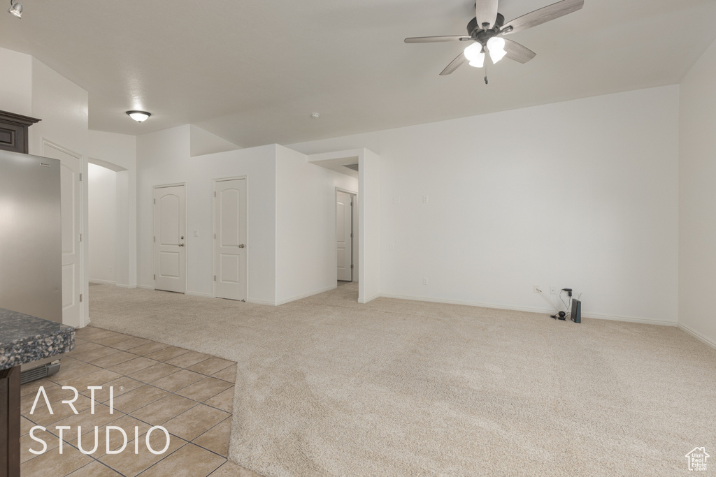 Unfurnished living room featuring light carpet and ceiling fan