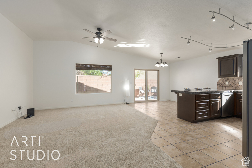 Kitchen with light tile patterned flooring, ceiling fan with notable chandelier, backsplash, dark brown cabinetry, and lofted ceiling