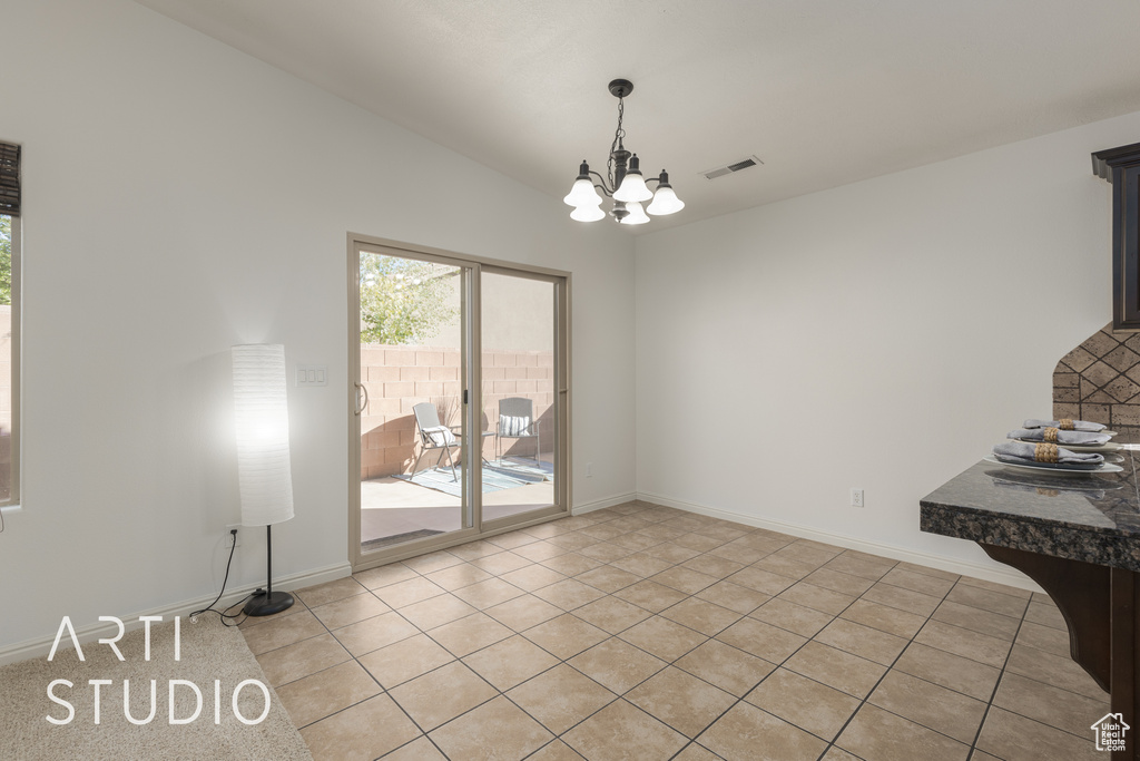 Unfurnished dining area featuring vaulted ceiling, an inviting chandelier, and light tile patterned floors