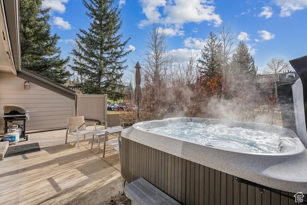 Wooden terrace featuring a hot tub and a grill