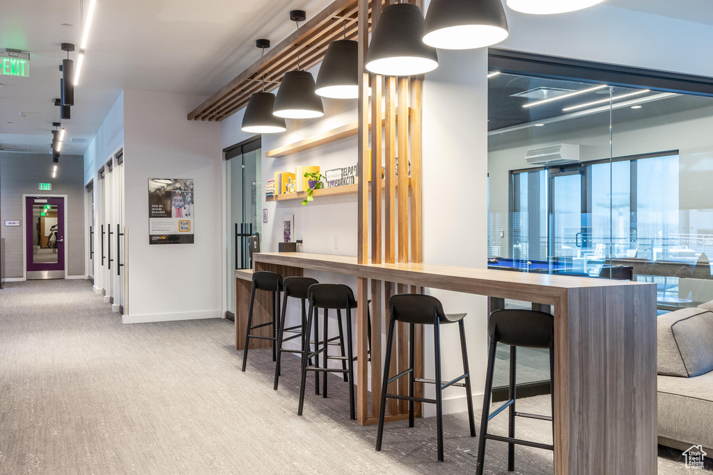 Kitchen featuring light carpet, an AC wall unit, hanging light fixtures, and a kitchen breakfast bar