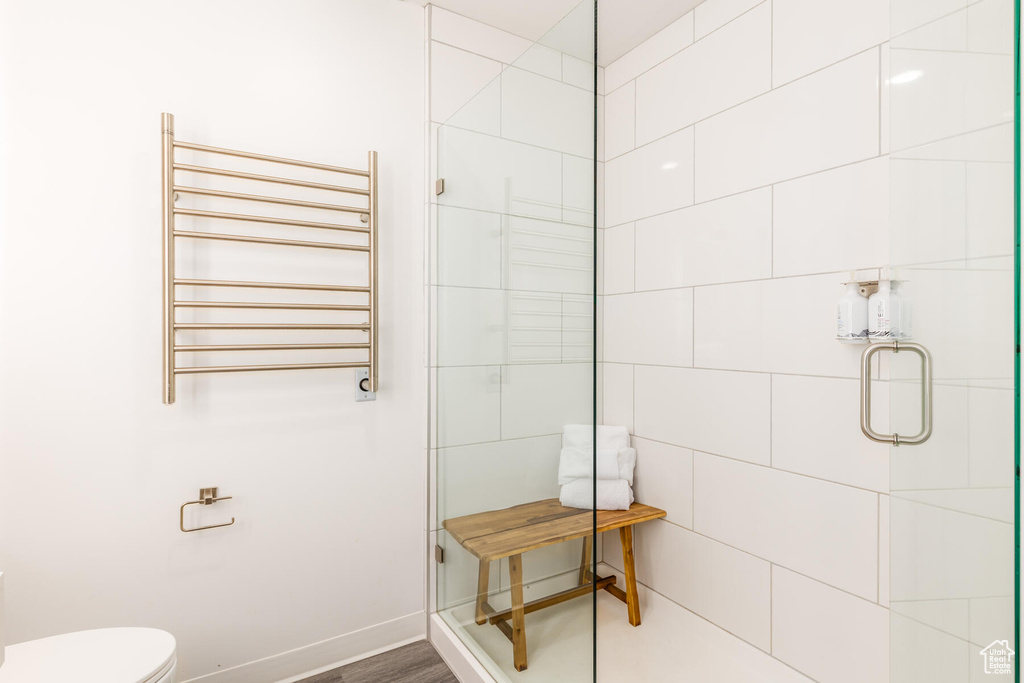 Bathroom with walk in shower, wood-type flooring, toilet, and radiator