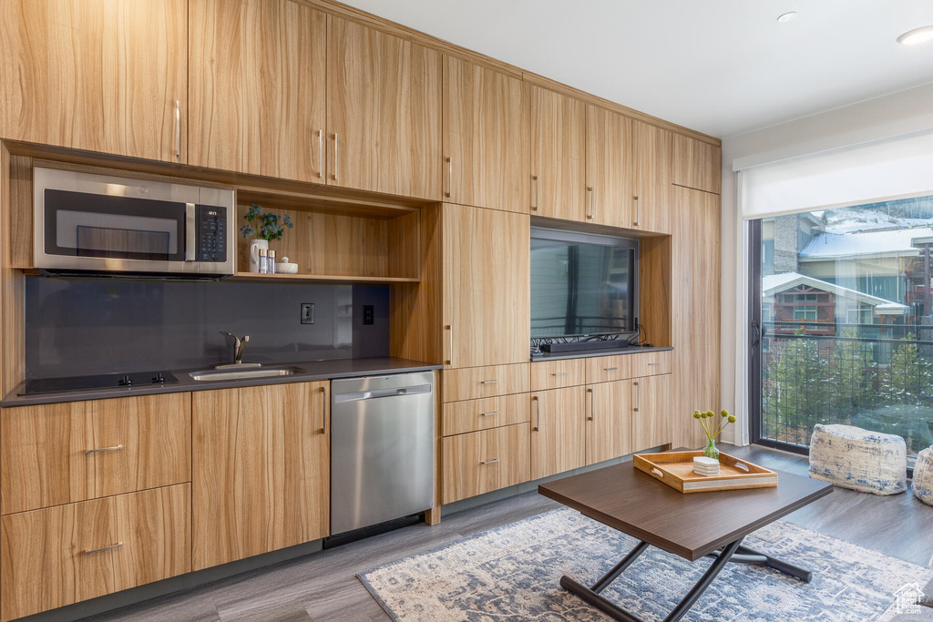 Kitchen featuring appliances with stainless steel finishes, sink, and light wood-type flooring