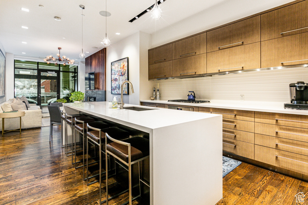 Kitchen featuring sink, a kitchen island with sink, a breakfast bar, and dark hardwood / wood-style flooring