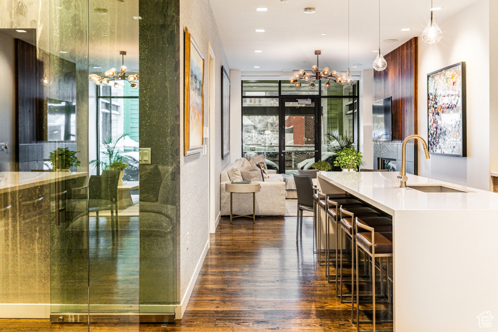 Interior space featuring dark hardwood / wood-style flooring, a breakfast bar, pendant lighting, a notable chandelier, and sink