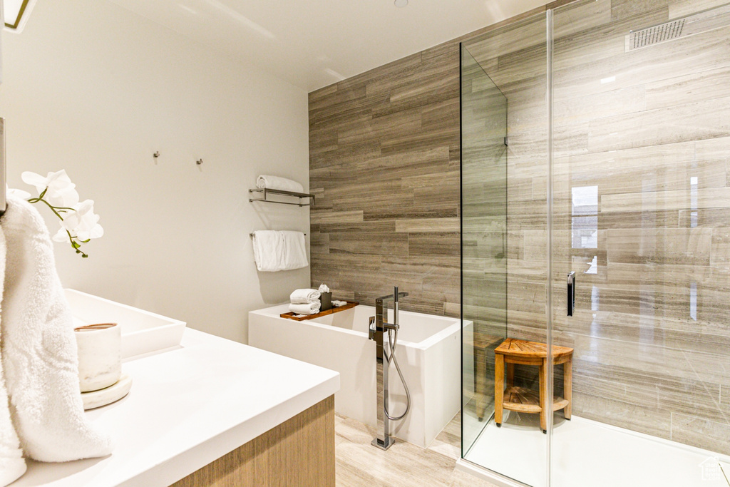 Bathroom with vanity, shower with separate bathtub, and hardwood / wood-style flooring