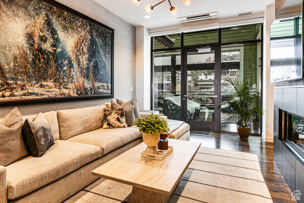 Living room featuring a notable chandelier, dark hardwood / wood-style floors, a tiled fireplace, and floor to ceiling windows