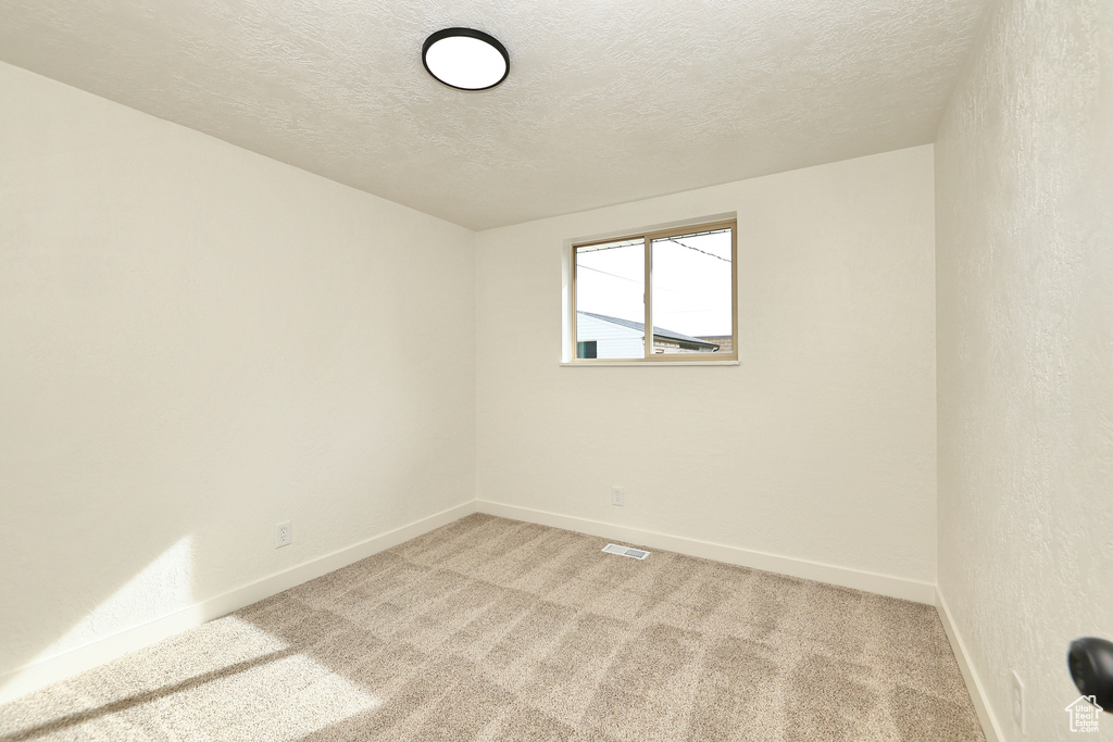 Carpeted empty room featuring a textured ceiling