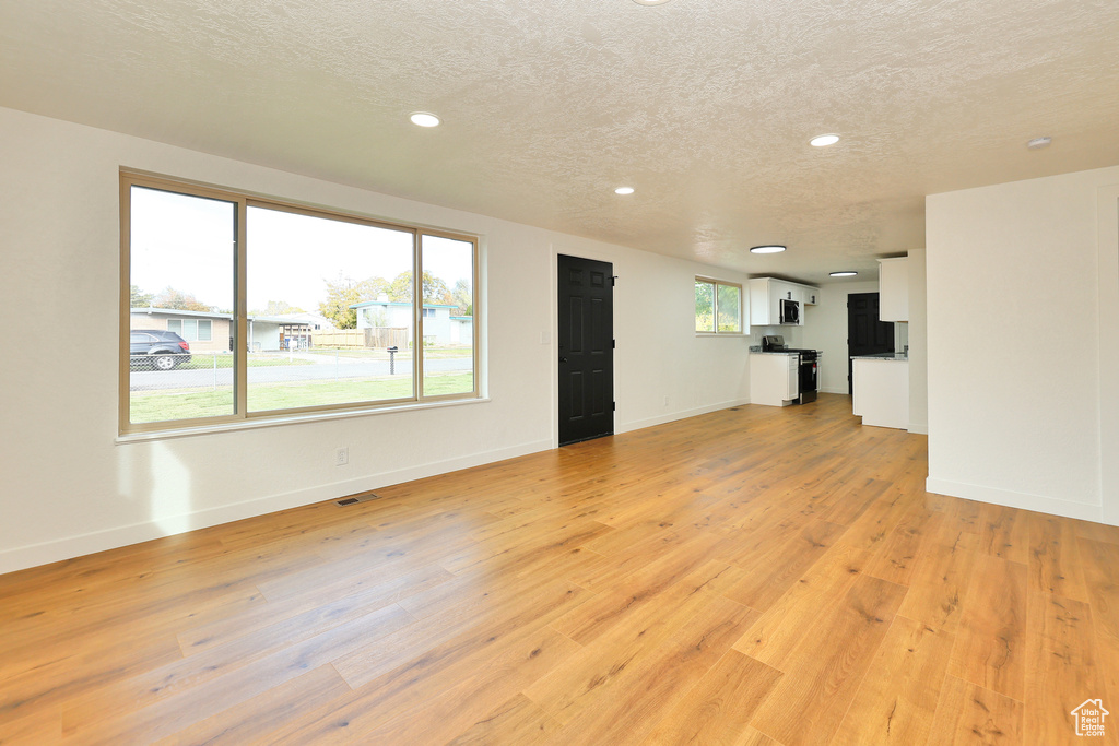 Unfurnished living room with a textured ceiling and light wood-type flooring