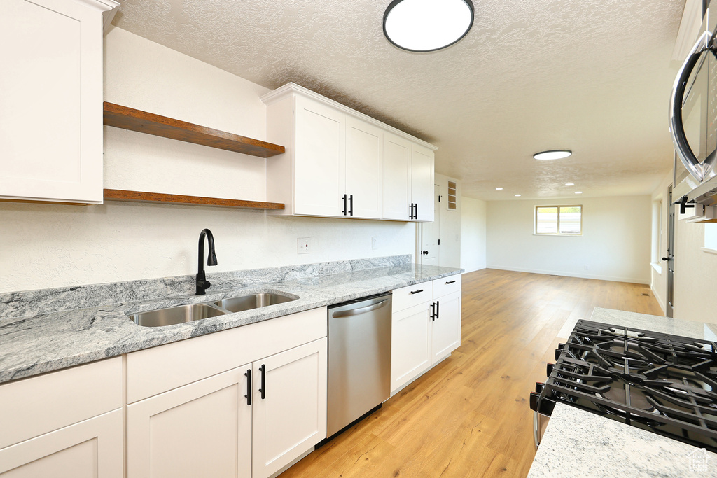 Kitchen featuring white cabinetry, stainless steel appliances, sink, and light wood-type flooring