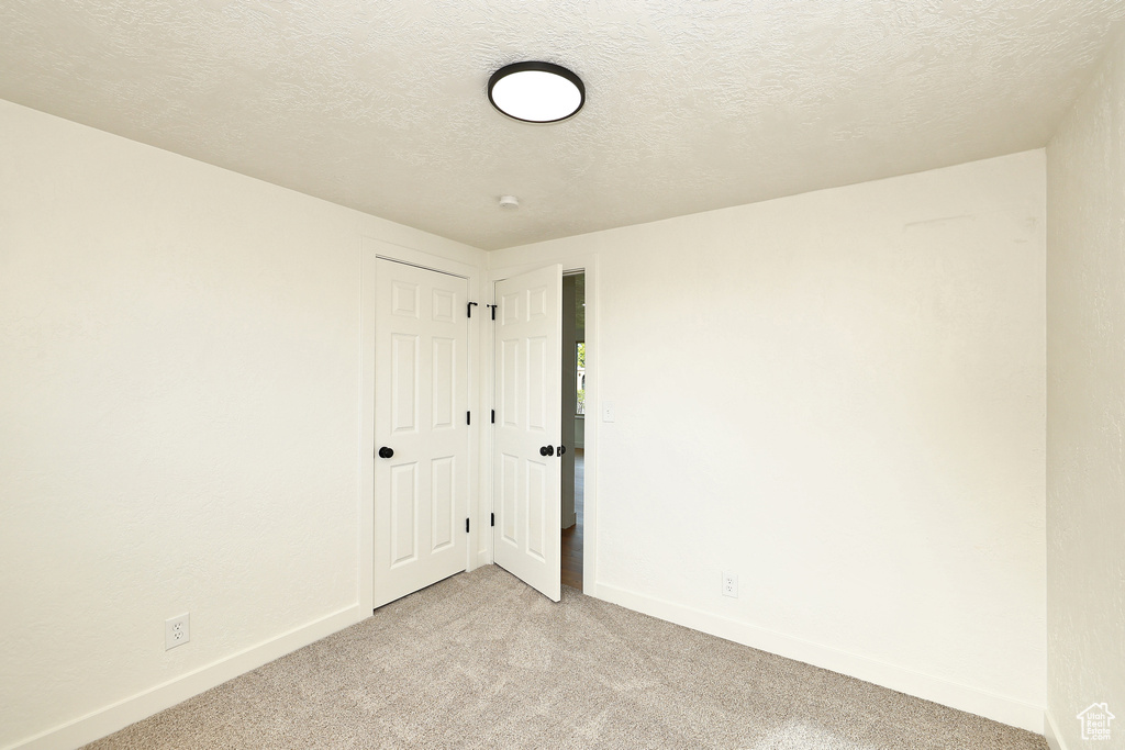 Empty room with a textured ceiling and light colored carpet