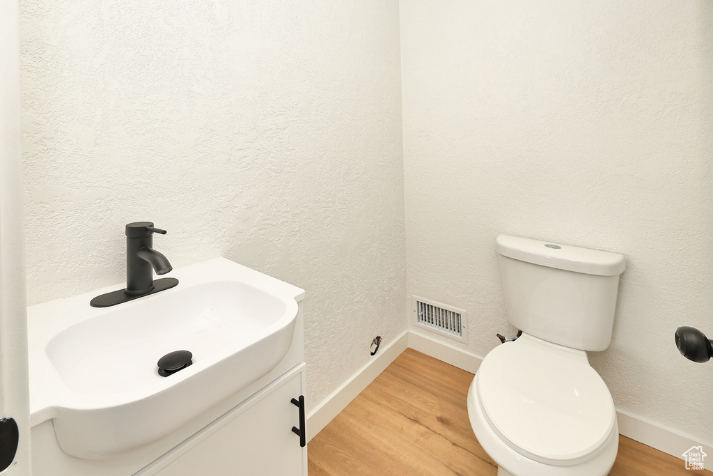 Bathroom featuring vanity, toilet, and wood-type flooring