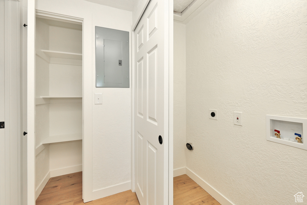 Washroom with hardwood / wood-style flooring, washer hookup, electric panel, and electric dryer hookup