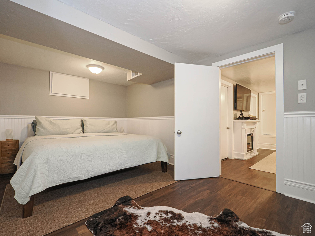 Bedroom with connected bathroom, a textured ceiling, and dark wood-type flooring