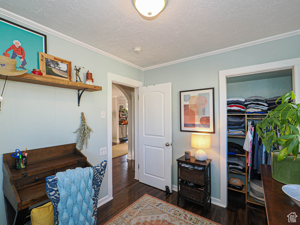 Bedroom featuring ornamental molding, dark wood-type flooring, and a textured ceiling