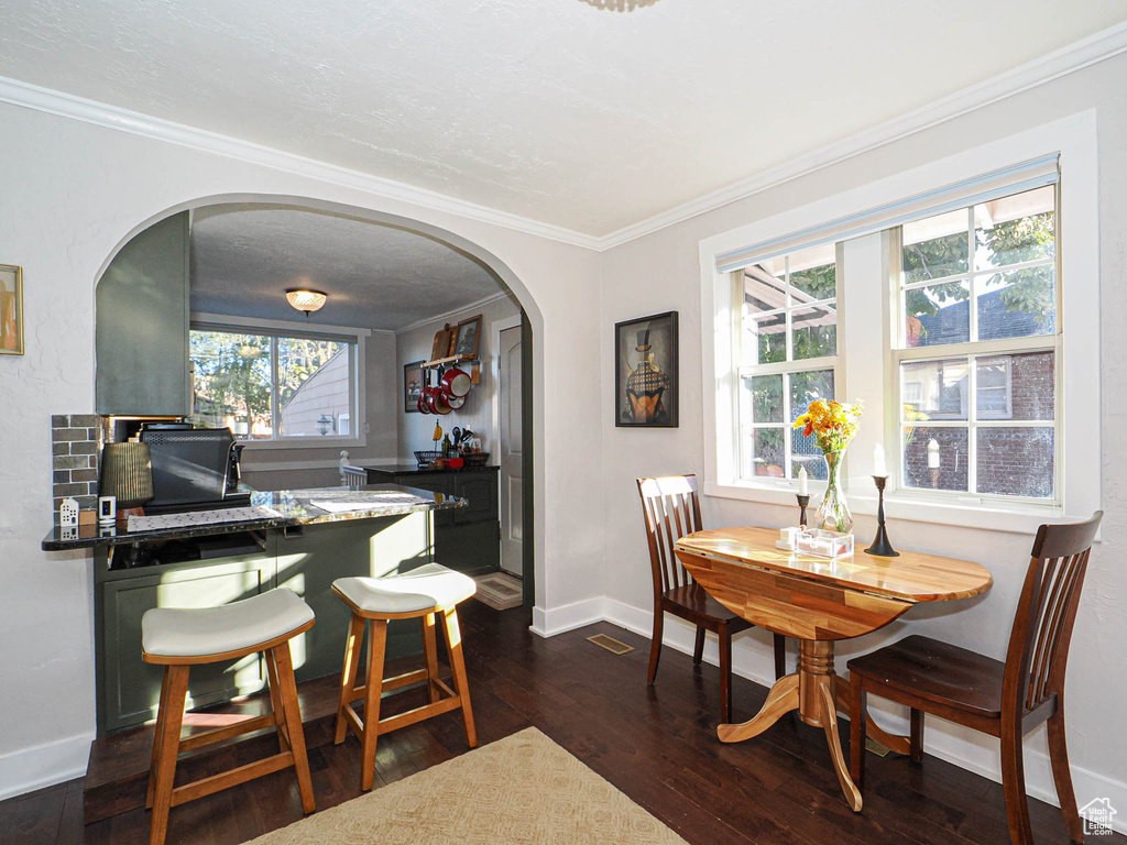 Dining space featuring crown molding and dark wood-type flooring