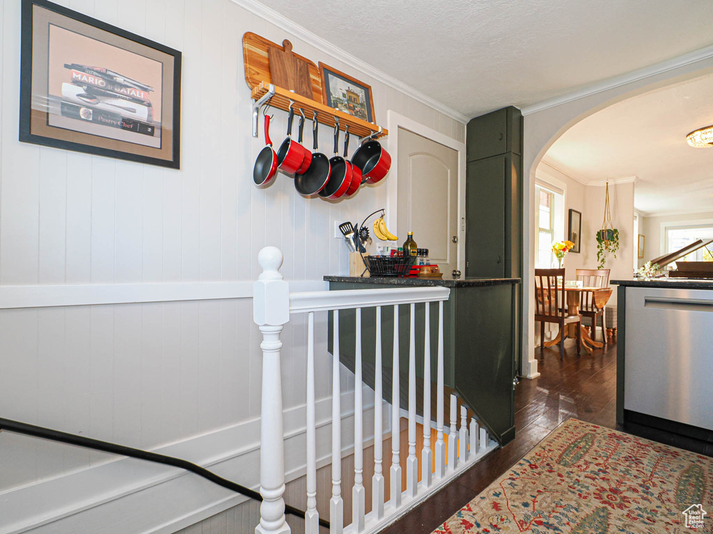 Hallway with wood walls, ornamental molding, and dark hardwood / wood-style flooring