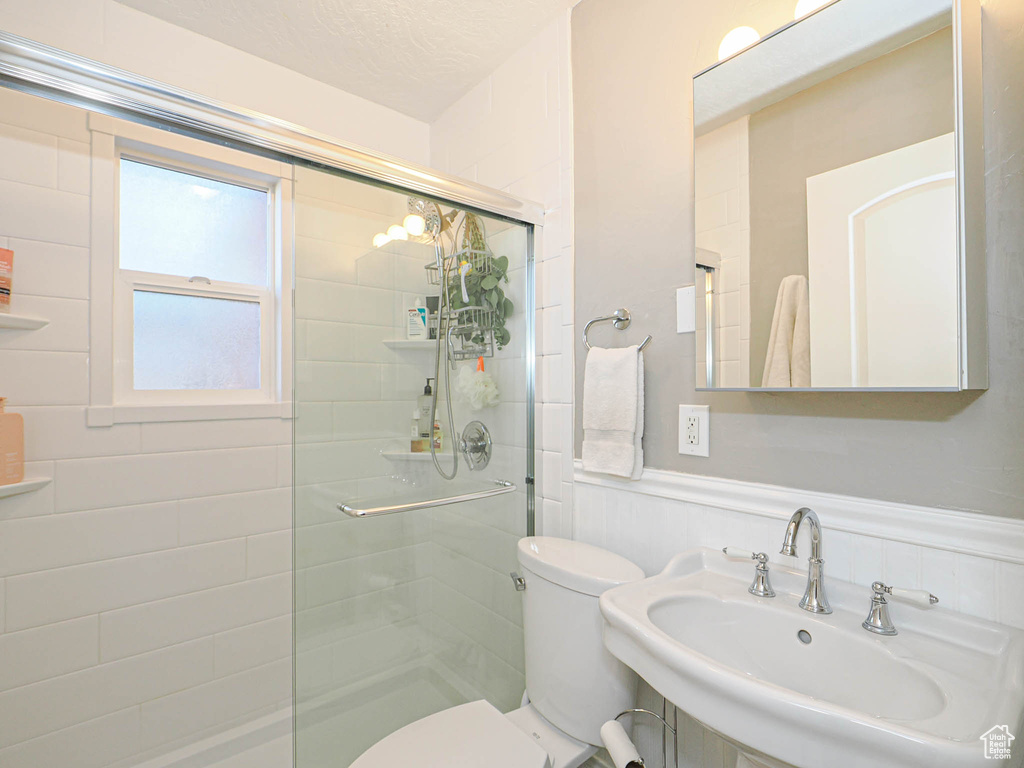 Bathroom featuring toilet, a shower with shower door, and sink