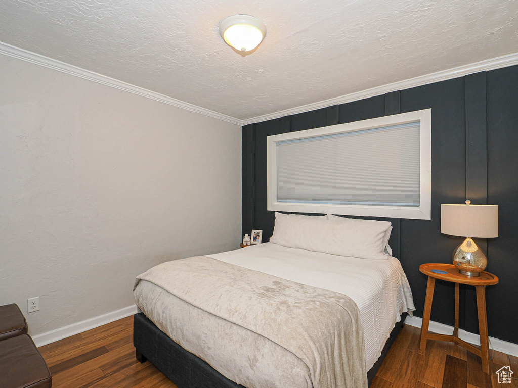 Bedroom featuring ornamental molding, a textured ceiling, and dark wood-type flooring