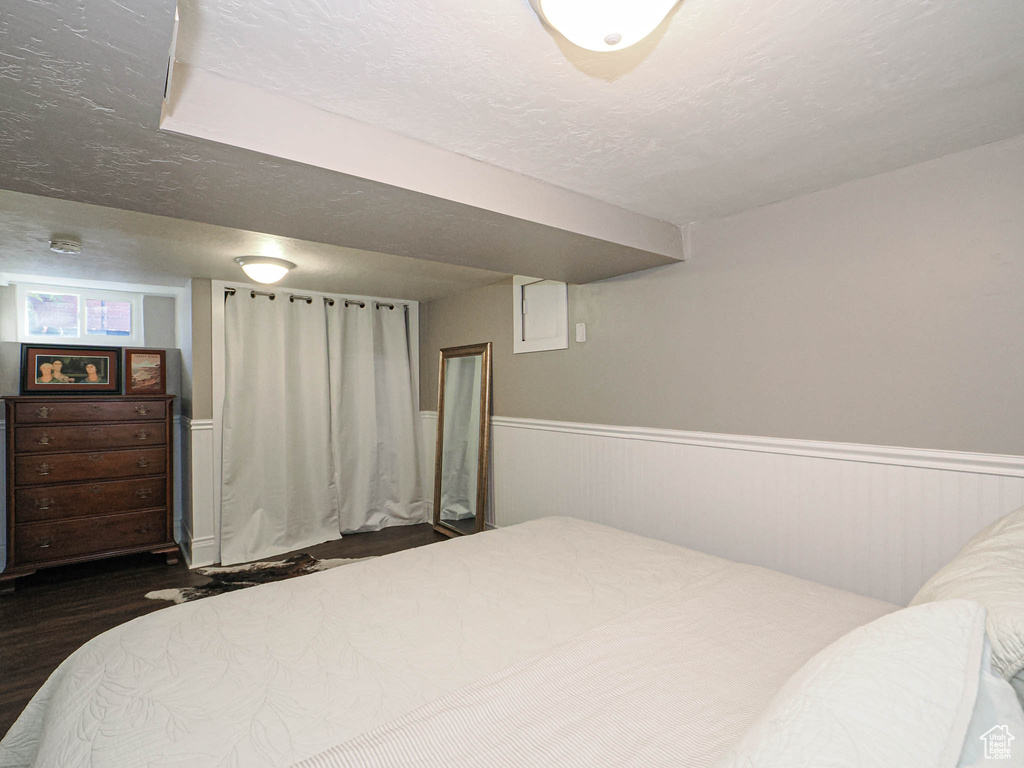 Bedroom with a textured ceiling and dark wood-type flooring