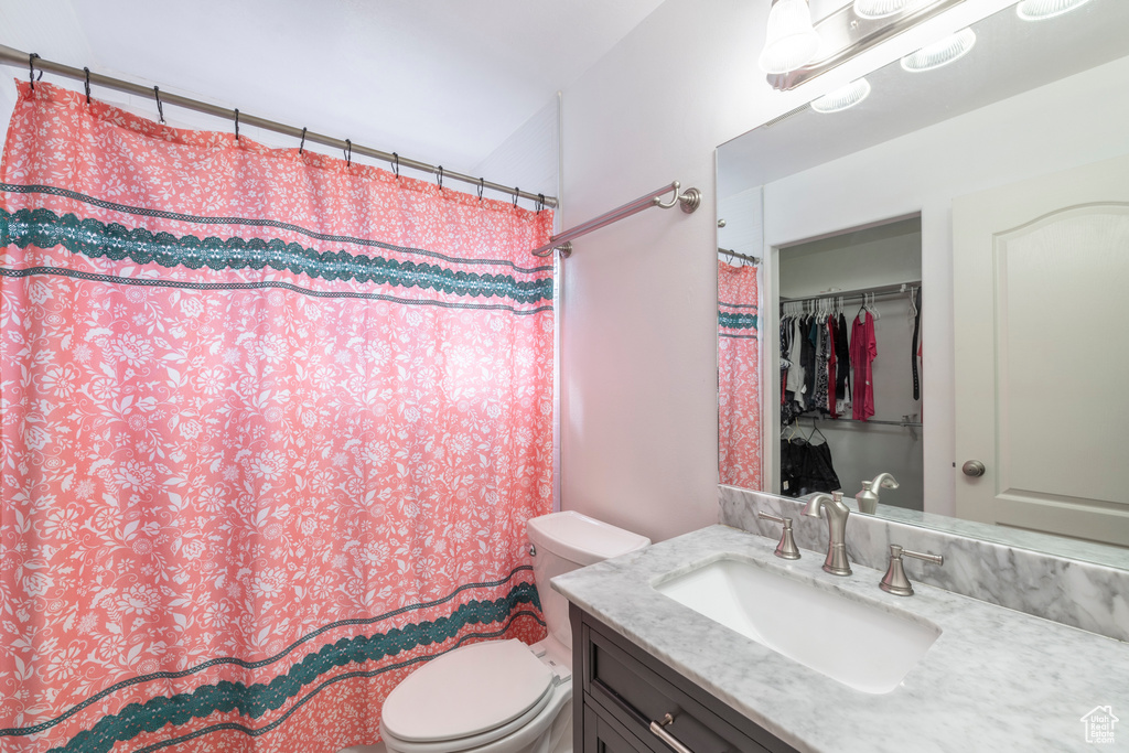 Bathroom with vanity, toilet, and curtained shower