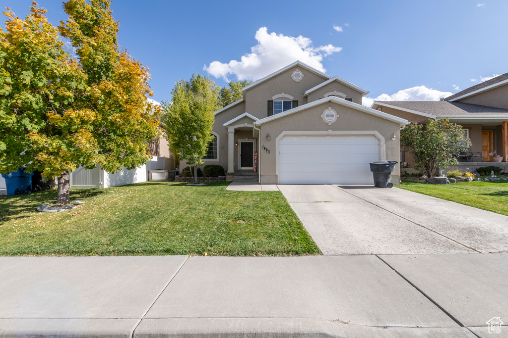 Front of property with a garage and a front lawn