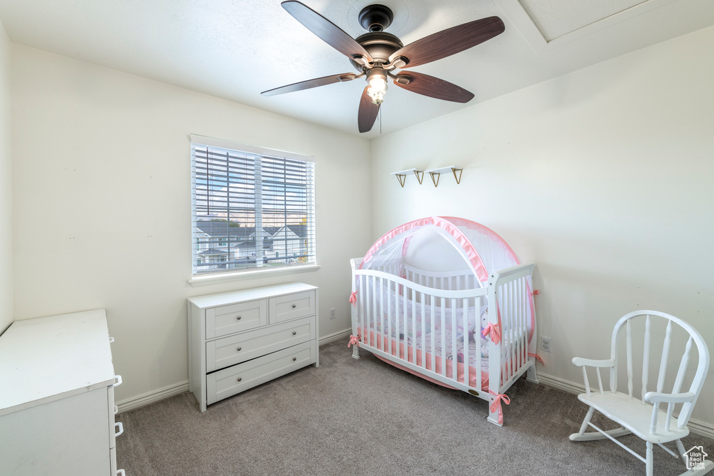 Bedroom featuring ceiling fan, light carpet, and a crib