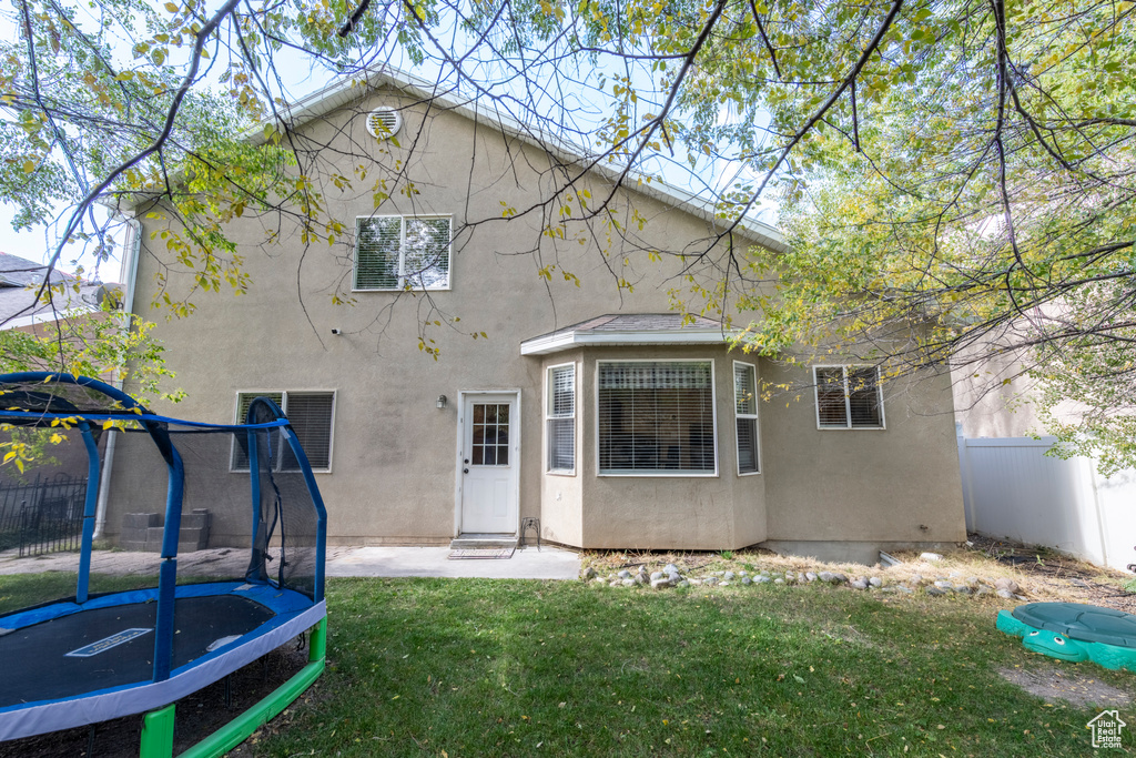 Rear view of property with a yard and a trampoline