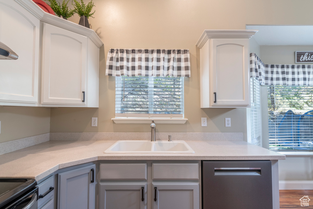 Kitchen with white cabinetry, appliances with stainless steel finishes, sink, and hardwood / wood-style floors