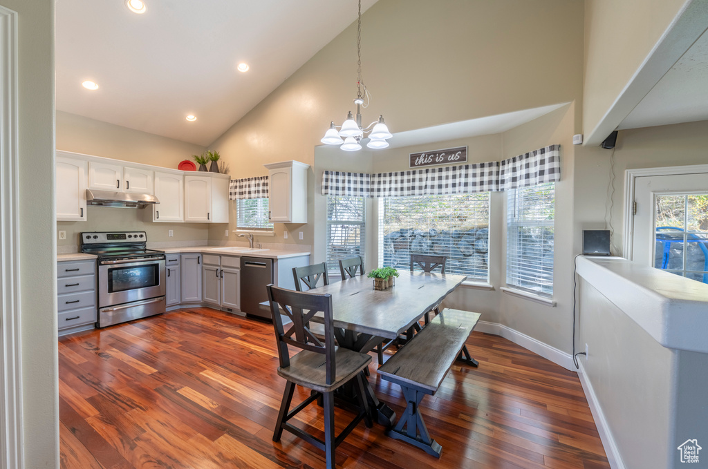 Dining room with high vaulted ceiling, an inviting chandelier, sink, and dark hardwood / wood-style floors