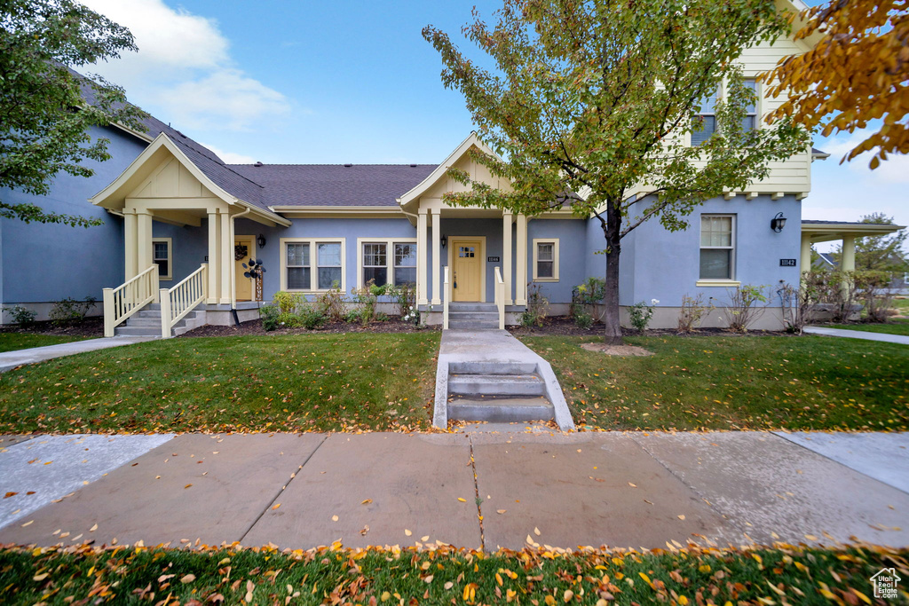 View of front of property with covered porch and a front yard