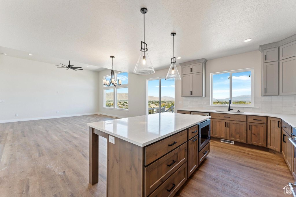 Kitchen featuring wood-type flooring, sink, a kitchen island, a textured ceiling, and pendant lighting