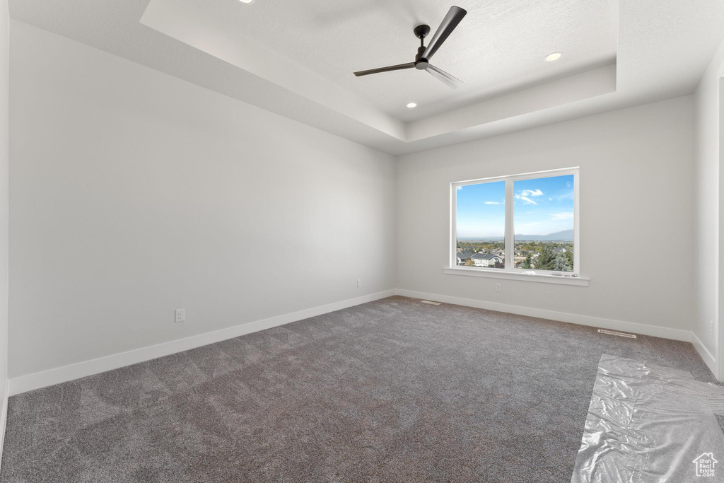 Carpeted empty room with a tray ceiling and ceiling fan