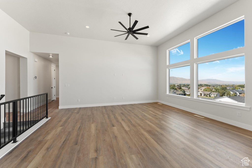 Unfurnished room featuring a mountain view, wood-type flooring, and ceiling fan