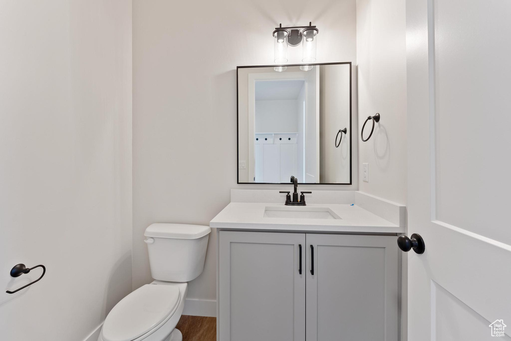 Bathroom featuring vanity, hardwood / wood-style flooring, and toilet