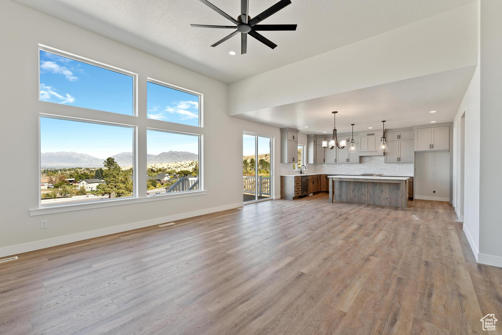 Unfurnished living room featuring a mountain view, light wood-type flooring, and a wealth of natural light