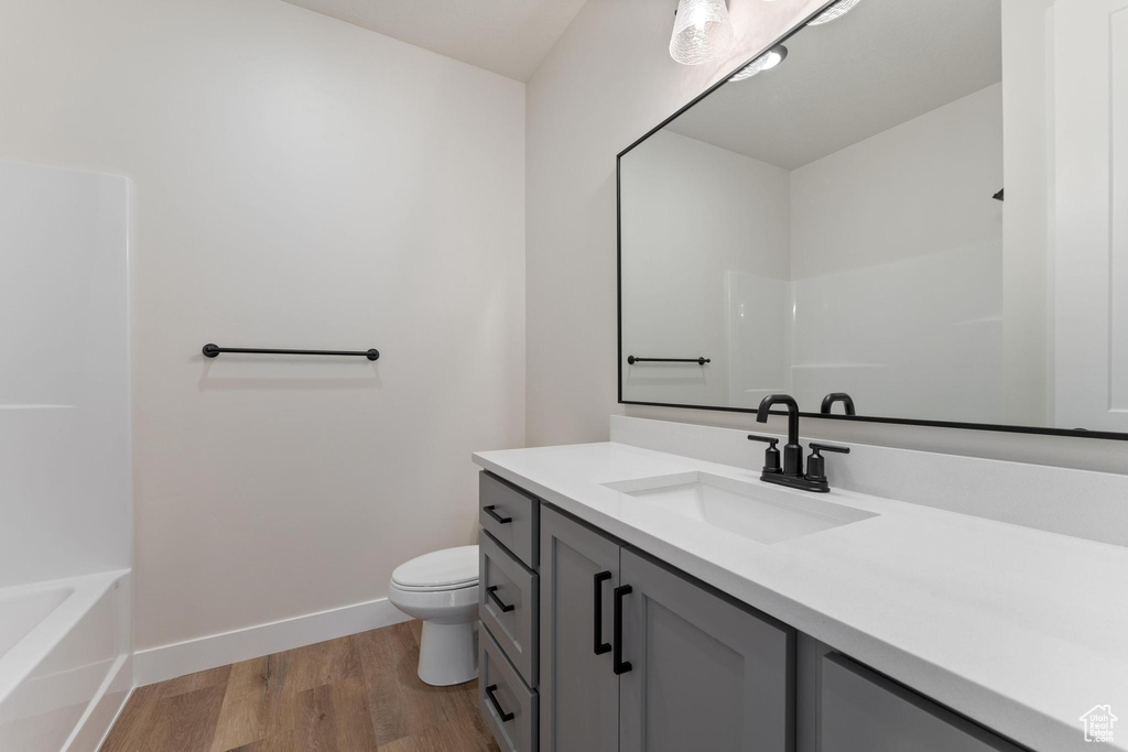 Full bathroom featuring vanity, hardwood / wood-style floors, independent shower and bath, and toilet