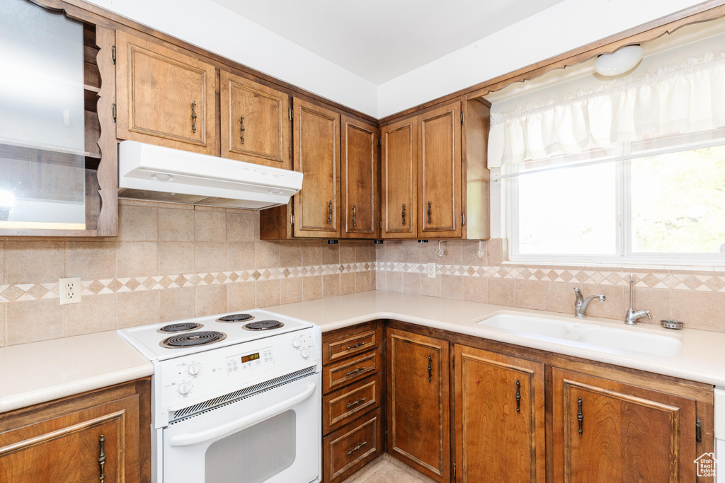 Kitchen with sink, white stove, and tasteful backsplash