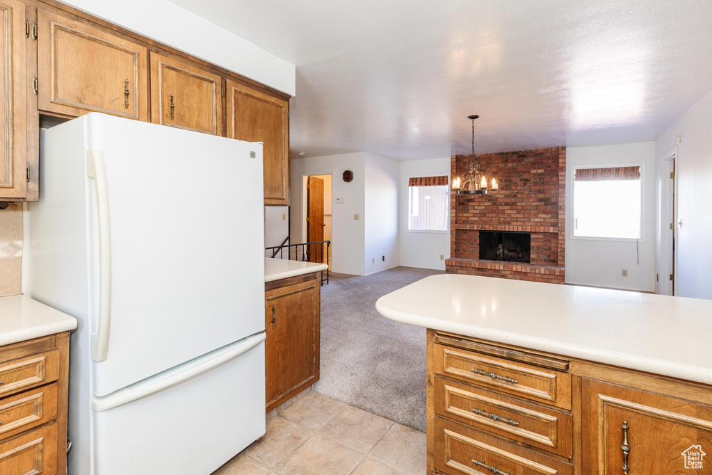 Kitchen featuring plenty of natural light, a brick fireplace, decorative light fixtures, and white refrigerator