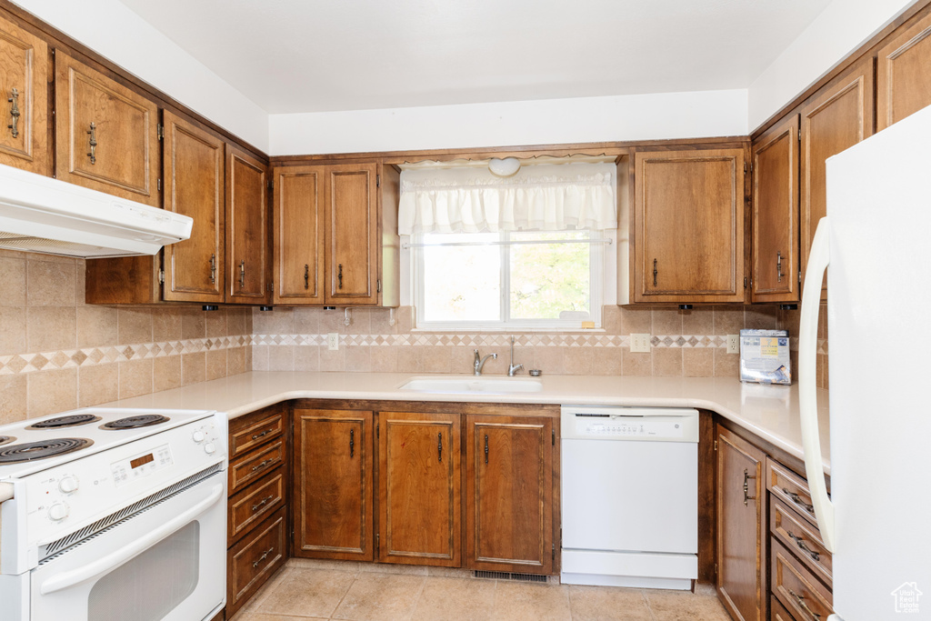 Kitchen with backsplash, sink, light tile patterned flooring, and white appliances