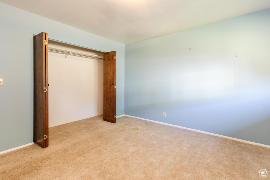 Unfurnished bedroom featuring a closet and light carpet