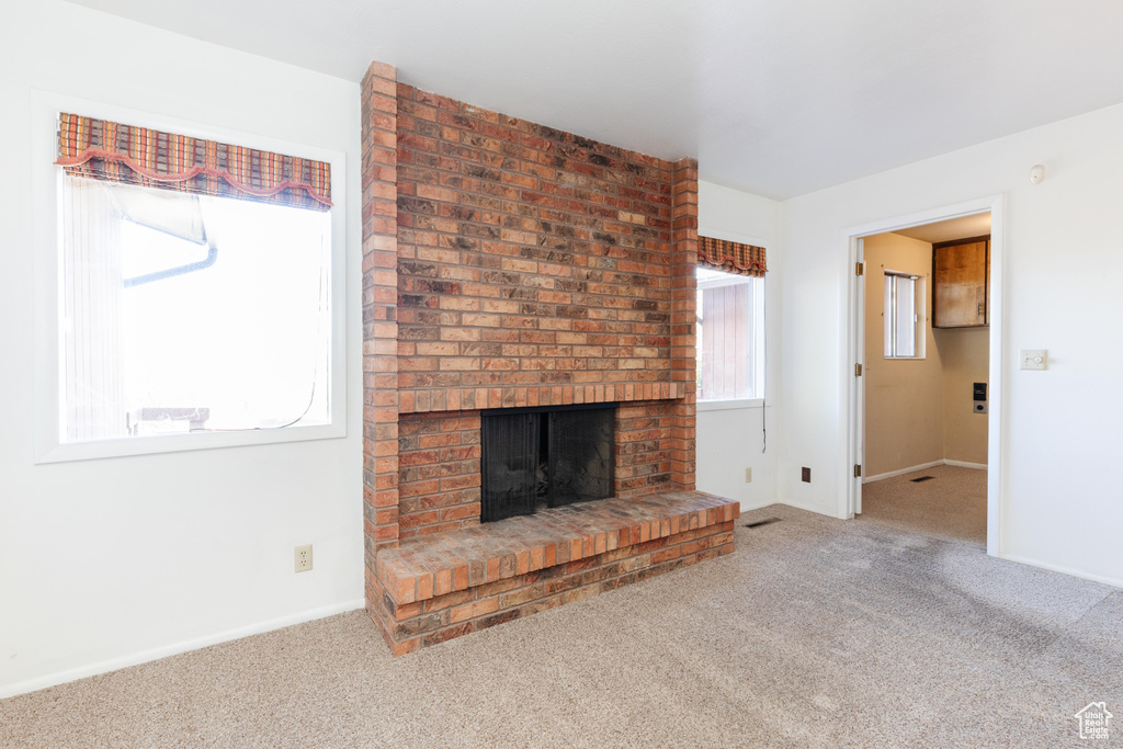 Unfurnished living room featuring a fireplace and carpet