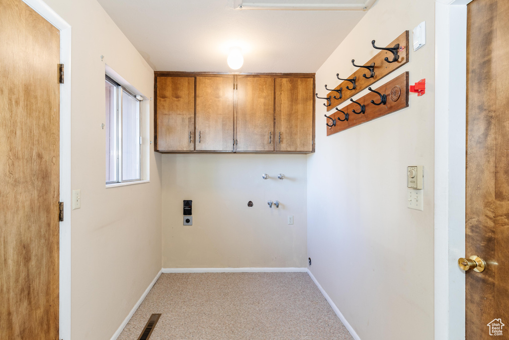 Washroom featuring hookup for an electric dryer, washer hookup, and cabinets