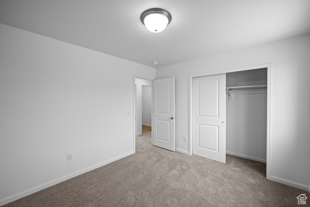 Unfurnished bedroom featuring carpet floors, baseboards, and a closet
