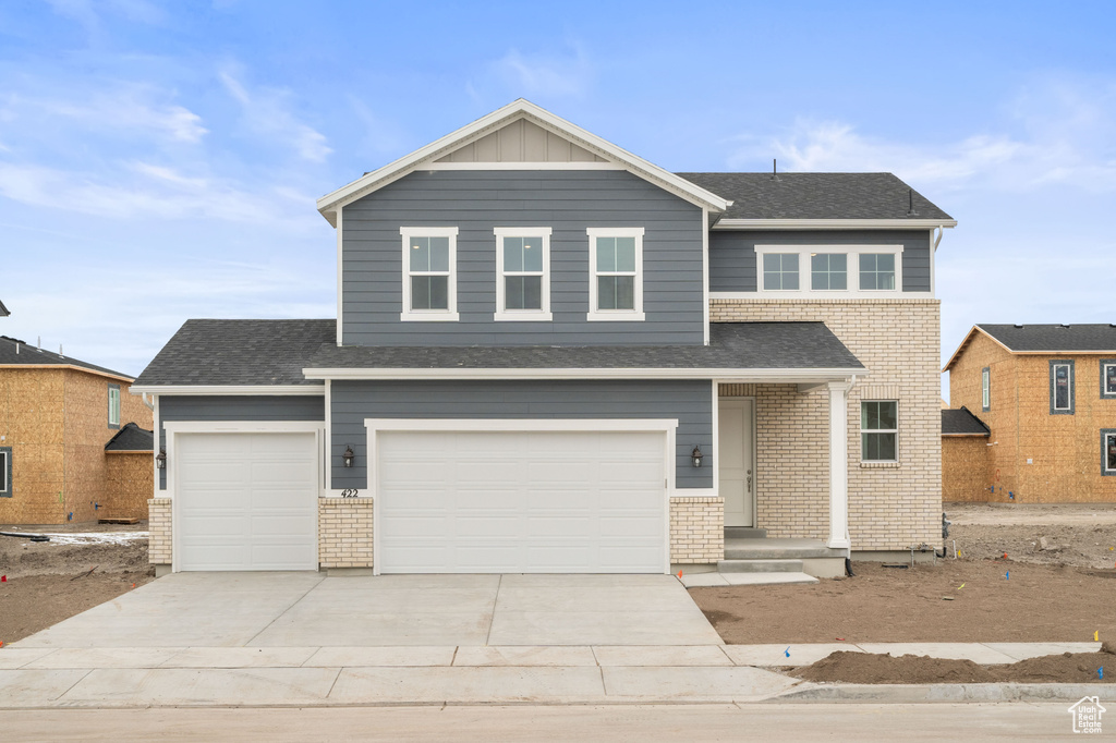 Traditional home featuring a garage, concrete driveway, and brick siding