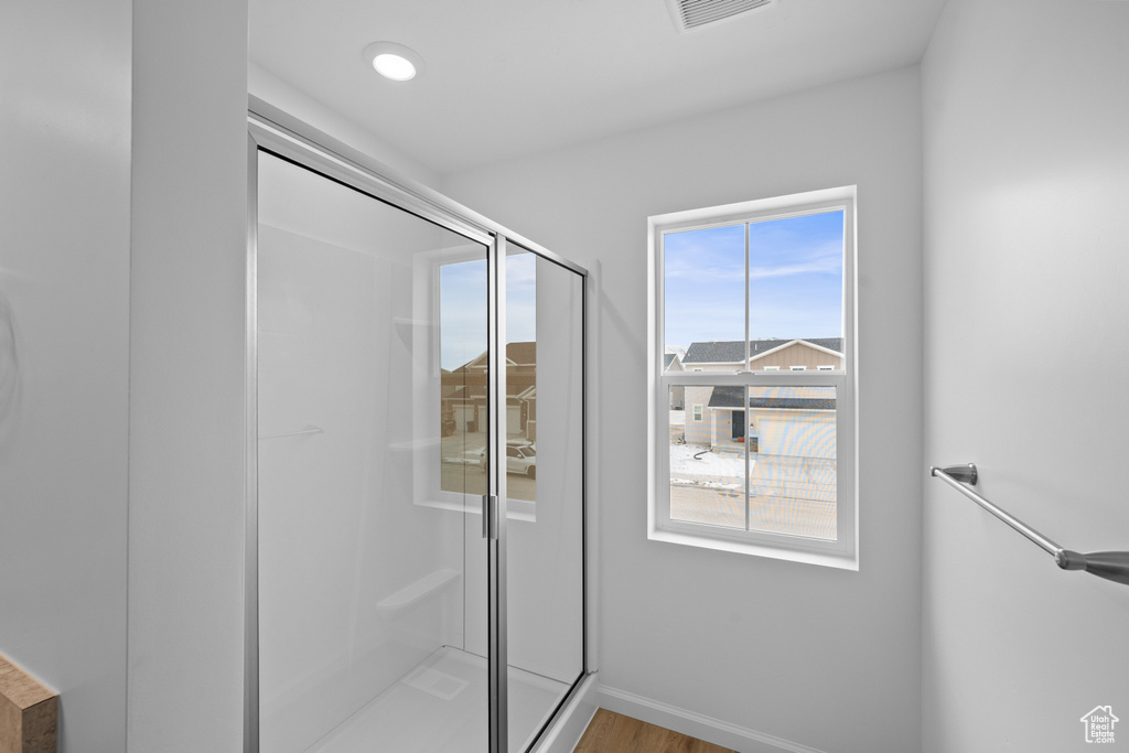 Bathroom with a stall shower, baseboards, and wood finished floors