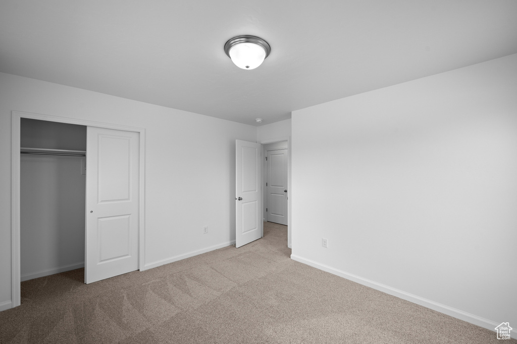 Unfurnished bedroom with carpet floors, baseboards, and a closet