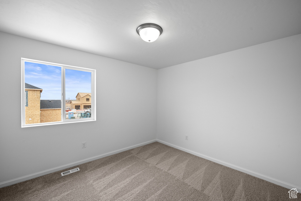 Carpeted spare room featuring baseboards