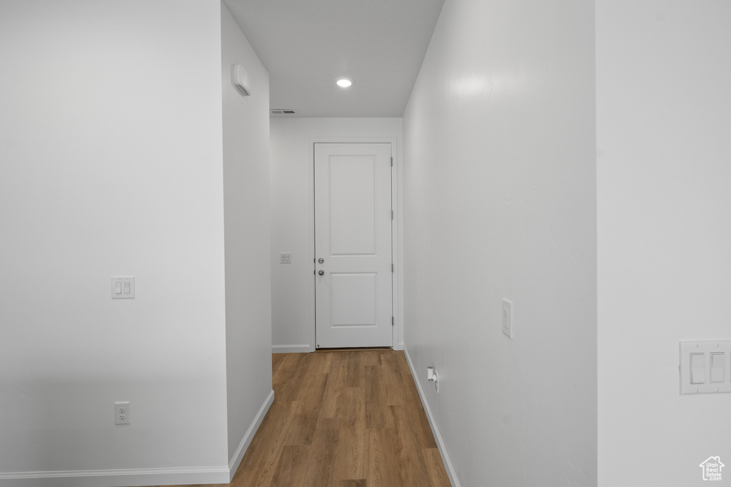 Hallway featuring baseboards, wood finished floors, and recessed lighting