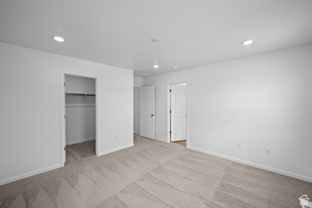 Unfurnished bedroom featuring carpet flooring, baseboards, recessed lighting, and a spacious closet